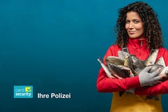 Person in roter Jacke hält mehrere Fische vor blauem Hintergrund.