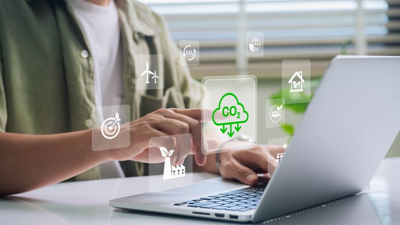 Eine Person sitzt am Tisch vor einem Laptop und sucht nach Informationen zum Thema Nachhaltigkeit